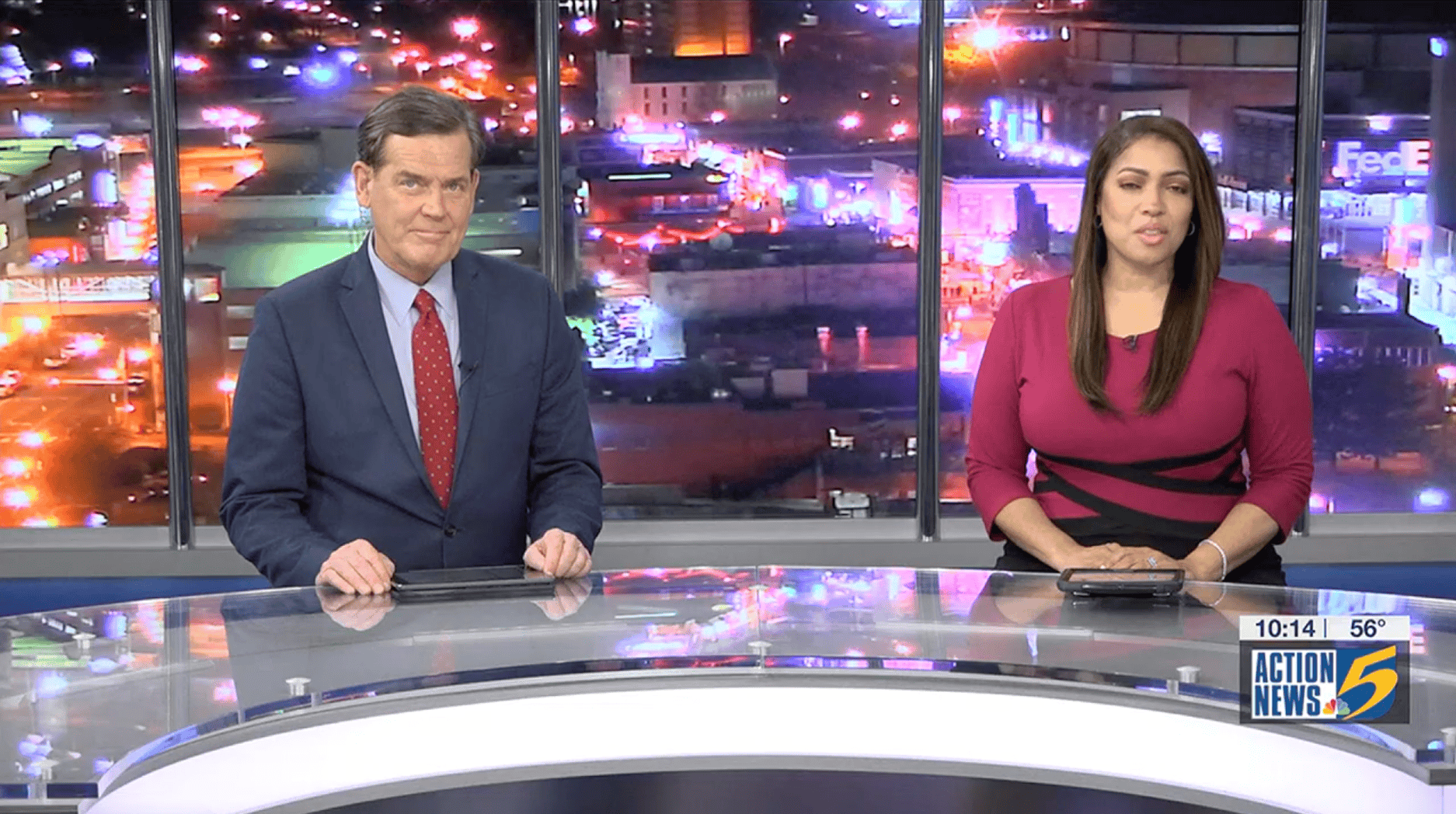 Screenshot 2025-07-28 at 2.49.20 PM Nighttime cityscape with colorful lights behind news anchors on Action News 5, Memphis, featuring city lights, urban environment, and television studio setting.