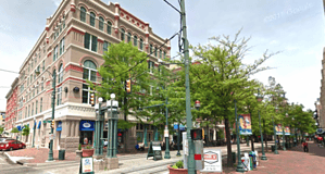 Historic Memphis Heritage building on a lively downtown street with trees, streetlights, and storefronts, showcasing Memphis architecture and urban charm.